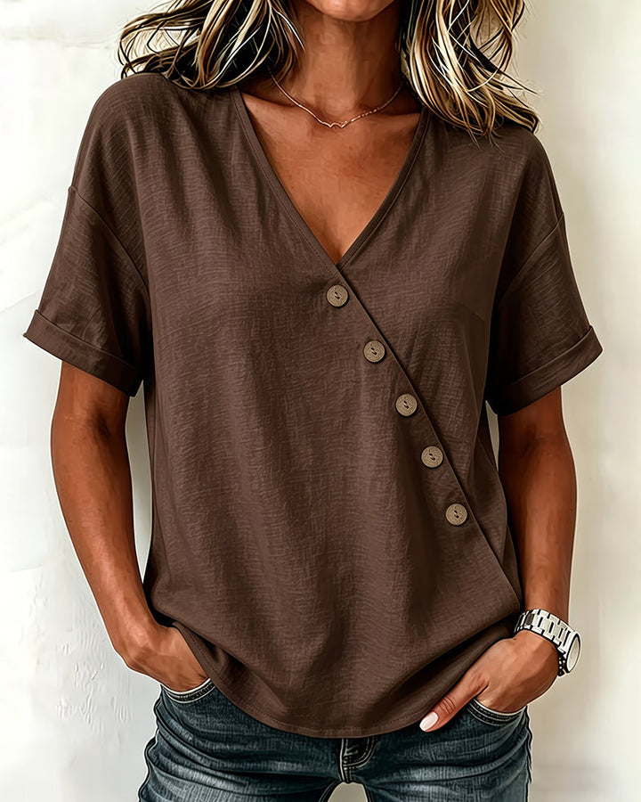 Close-up of the unique asymmetrical button detail and v-neckline on the navy blue blouse.