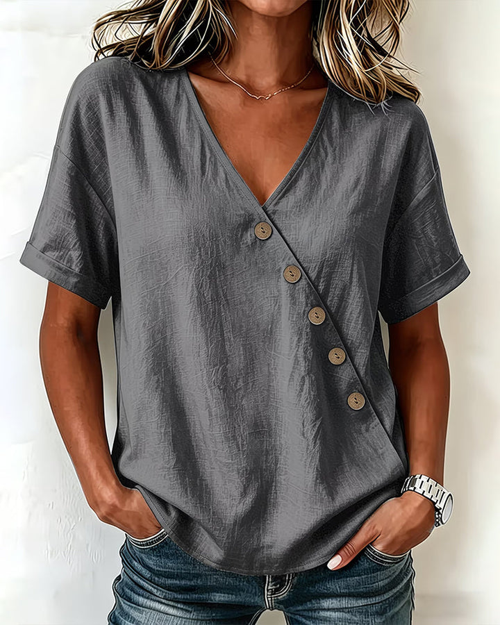 Woman walking outdoors wearing the light gray asymmetrical button blouse, showcasing its flowy fit.