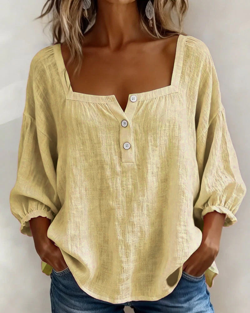 The white Anya blouse draped over a hanger, showing its flowy material.