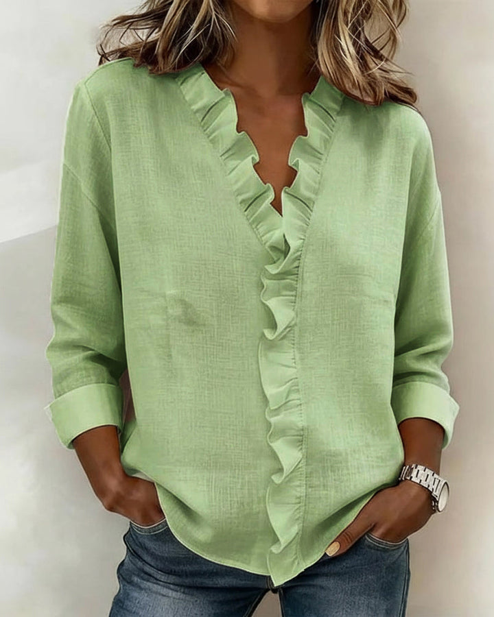 Model looking over her shoulder, showcasing the back detail of the pink ruffled V-neck blouse.