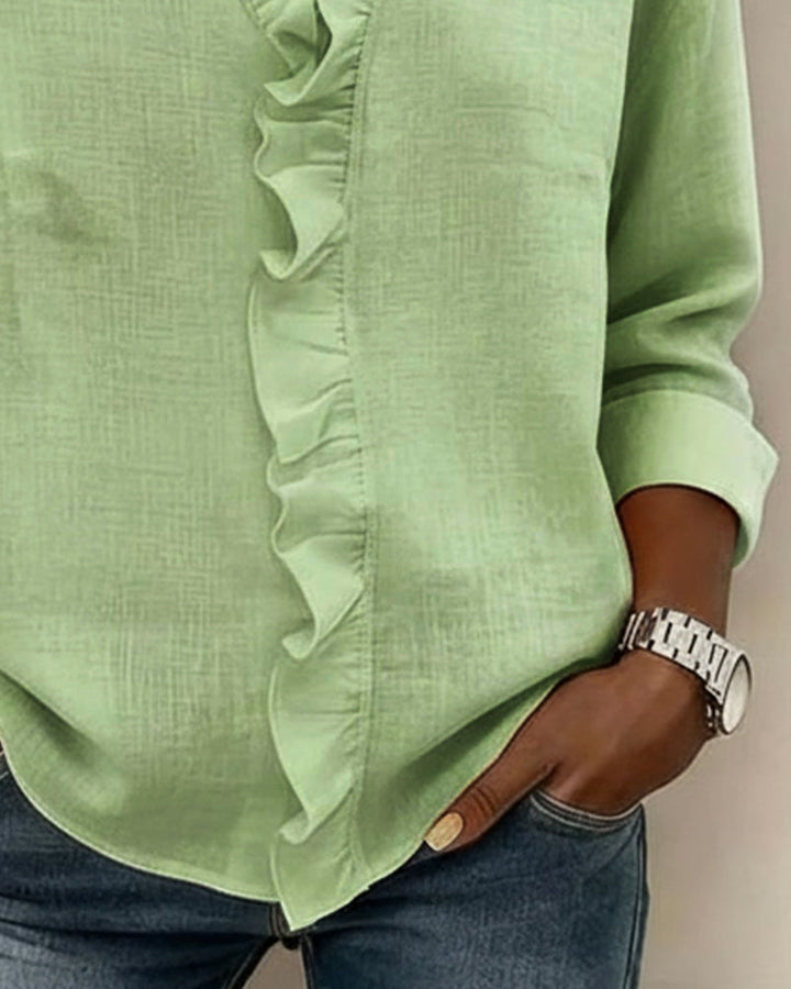 Front view of the black ruffled V-neck blouse on a hanger, highlighting its drape.