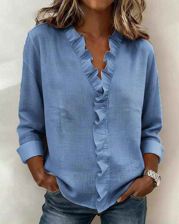A conceptual shot of the white ruffled V-neck blouse with subtle accessories for styling inspiration.