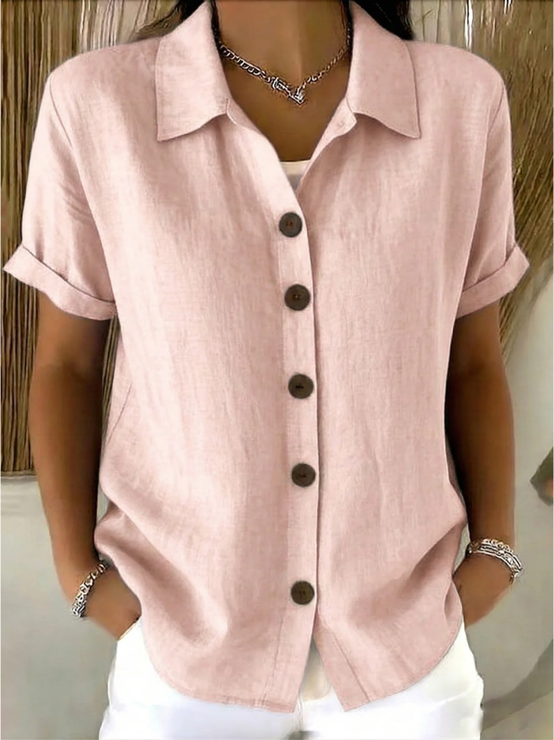 Lifestyle shot of a woman wearing the white button-front shirt paired with light pants, enjoying a casual outdoor setting.