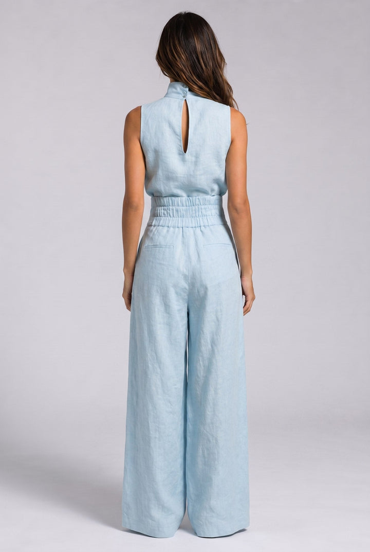 A model walking in a military green jumpsuit, showcasing its effortless elegance and wide-leg silhouette.