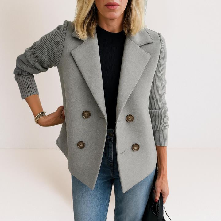Side profile of a woman wearing the grey Evadne knit sleeve blazer, highlighting the structured shoulders and sleeve texture.