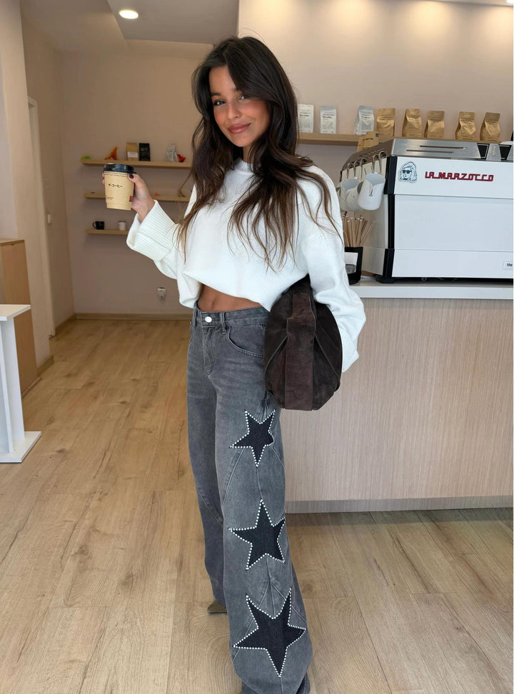 Model seated, highlighting the relaxed fit and how the star print straight jeans drape naturally.