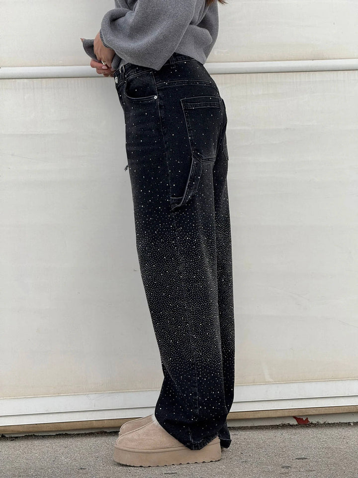 Model showcasing the crazy fit of the black embellished carpenter jeans from a front angle.