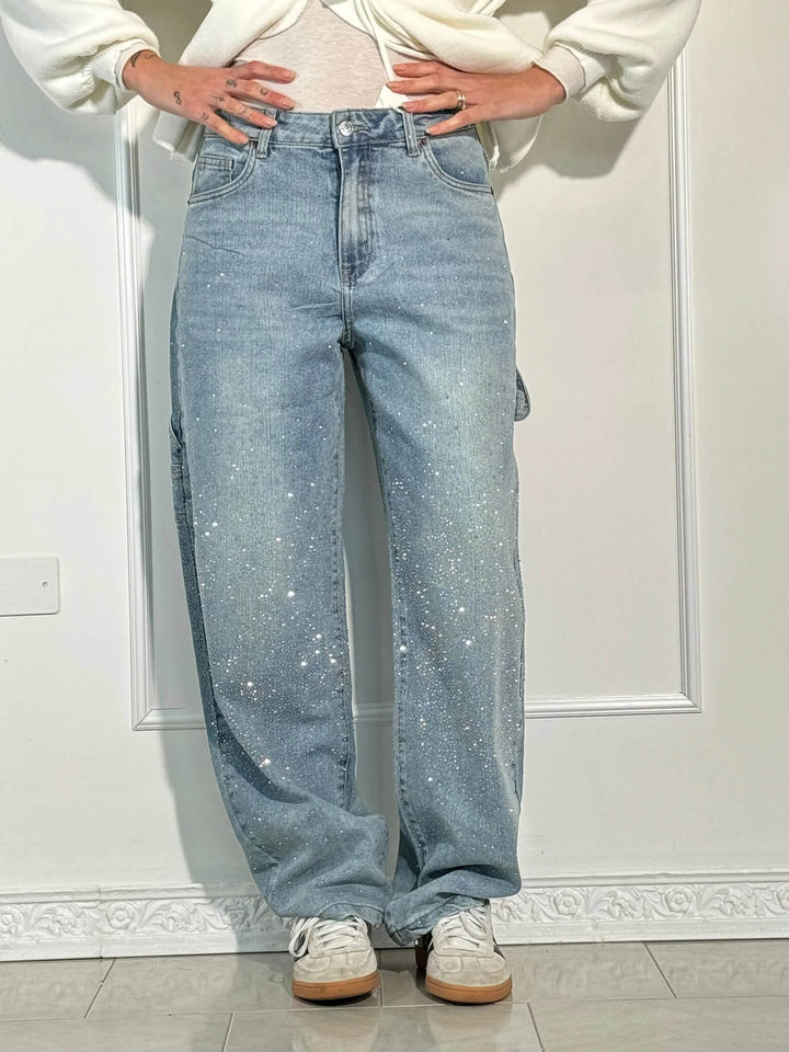 Detail shot of the waistband and button closure on the dark blue embellished jeans.