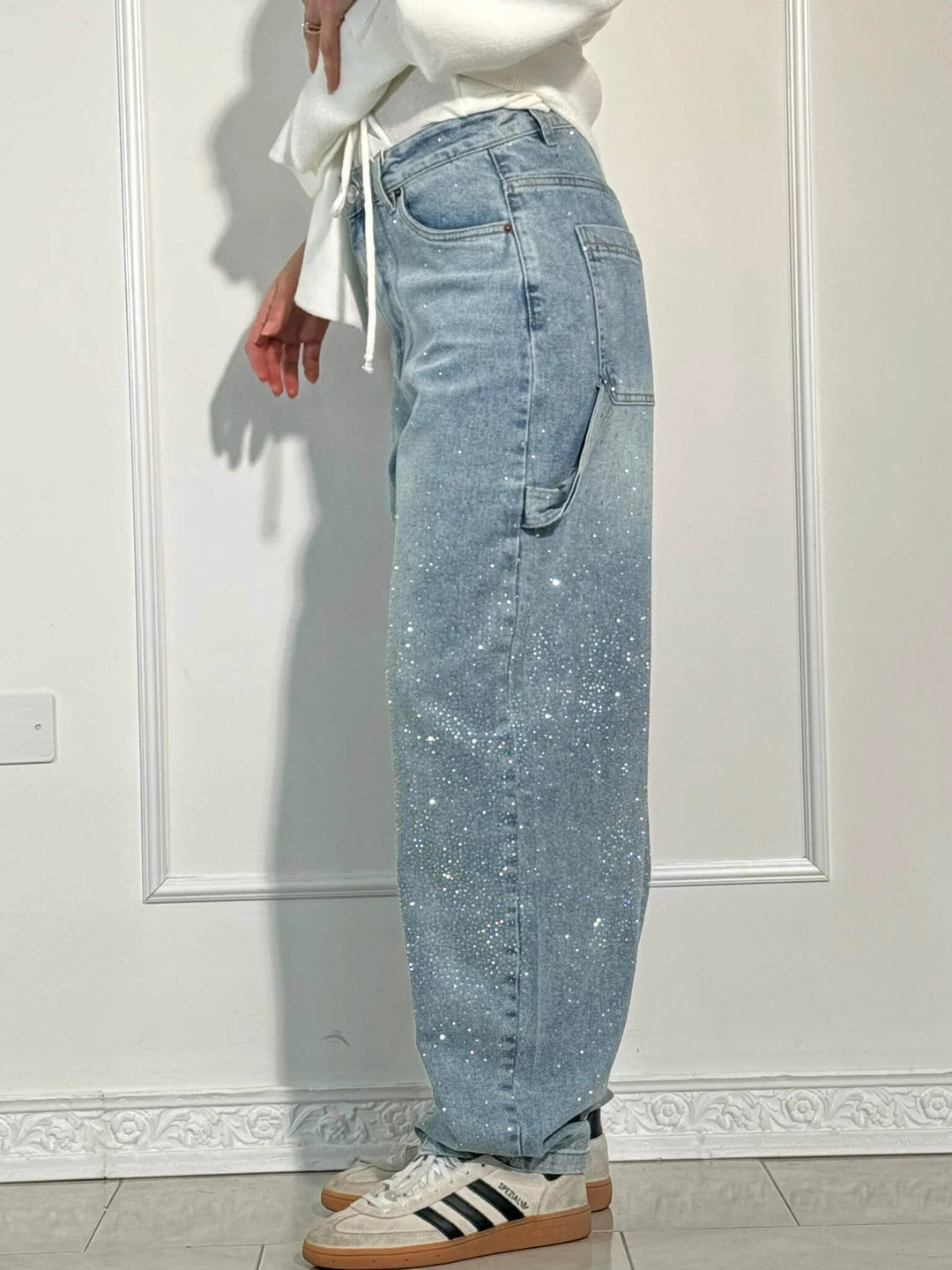 Lifestyle shot of a woman walking in the dark blue embellished carpenter jeans.