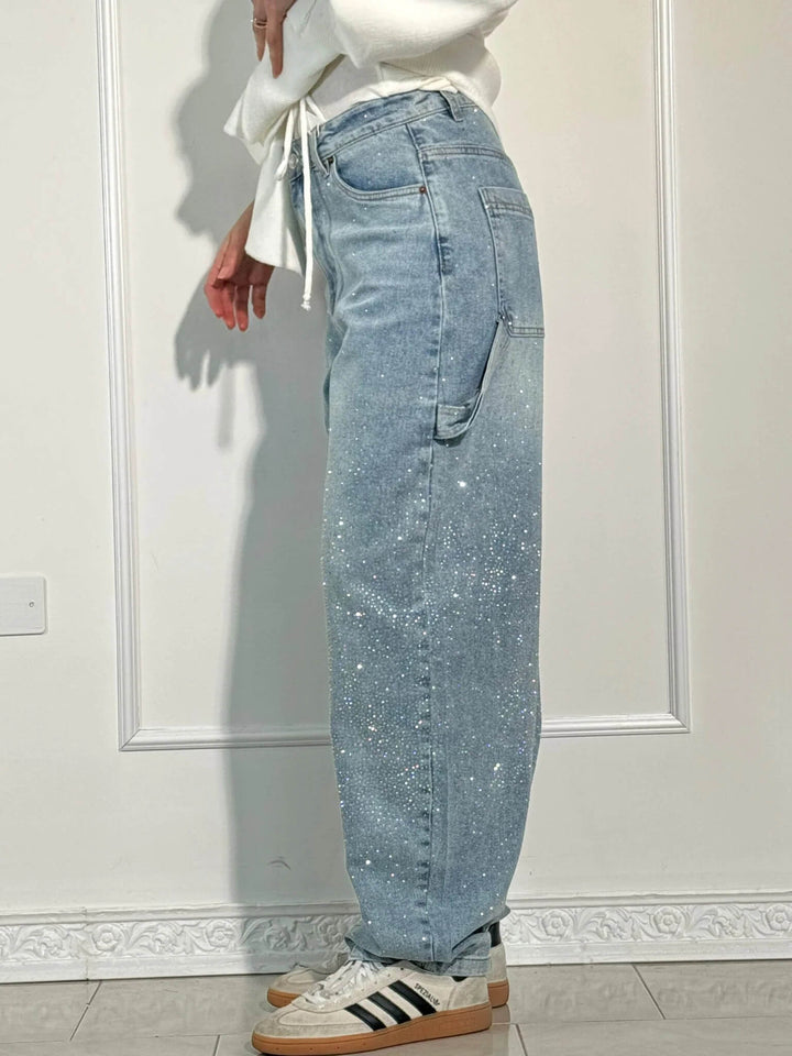 Lifestyle shot of a woman walking in the dark blue embellished carpenter jeans.