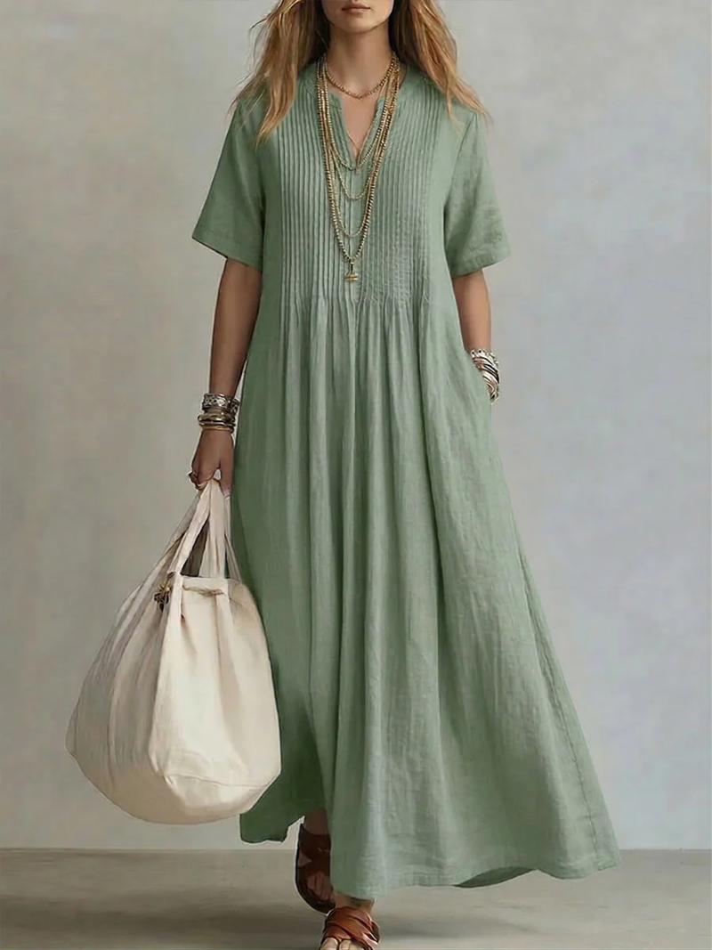 Close-up detail of the delicate pleating on the bodice and skirt of the flowy maxi dress, highlighting texture.