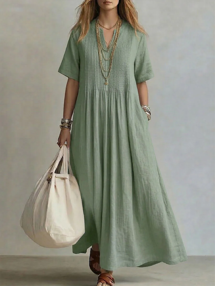 Close-up detail of the delicate pleating on the bodice and skirt of the flowy maxi dress, highlighting texture.