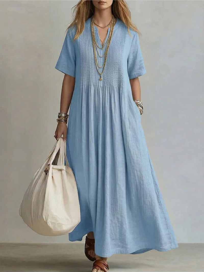 Side profile of a woman gracefully walking in the forest green pleated maxi dress, illustrating movement.