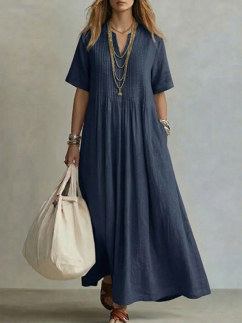 Lifestyle shot of a woman enjoying a warm evening, wearing the yellow pleated maxi dress with subtle accessories.