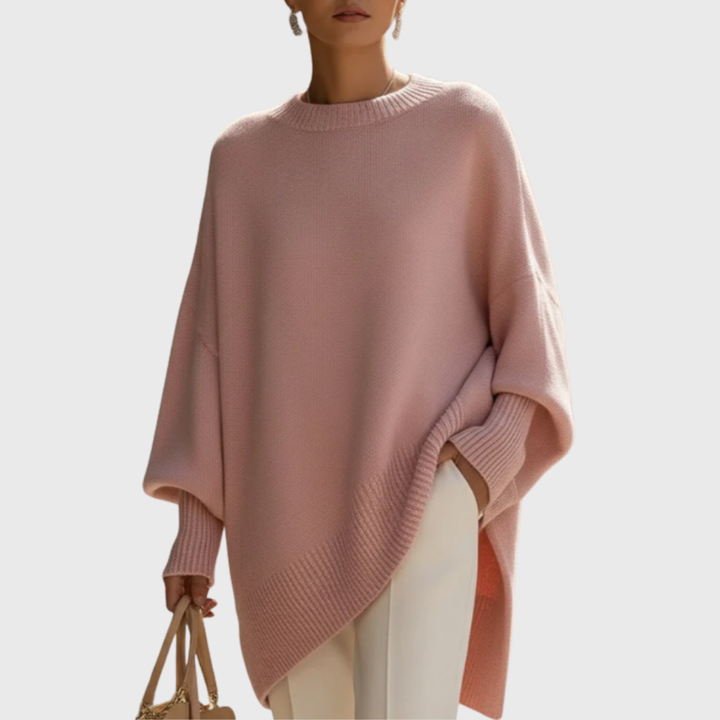 Model wearing the Solana poncho pullover in rose, styled casually with jeans, demonstrating its versatility.