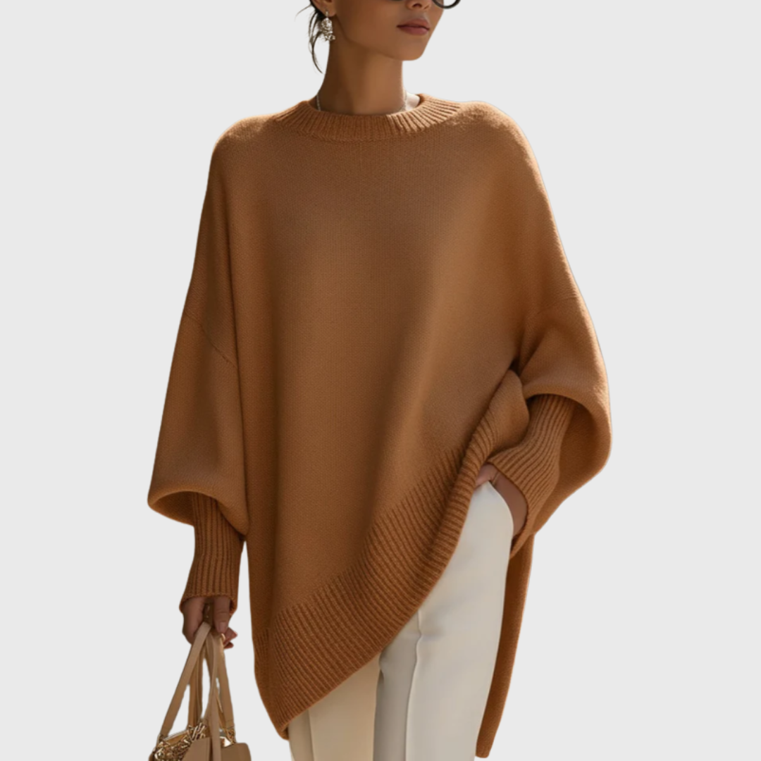 Lifestyle shot of a woman enjoying coffee outdoors while wearing the comfortable Solana poncho pullover in grey.