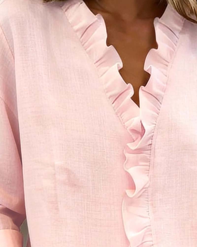 Side profile of a model wearing a pink ruffle V-neck long-sleeve blouse, highlighting the sleeve length.
