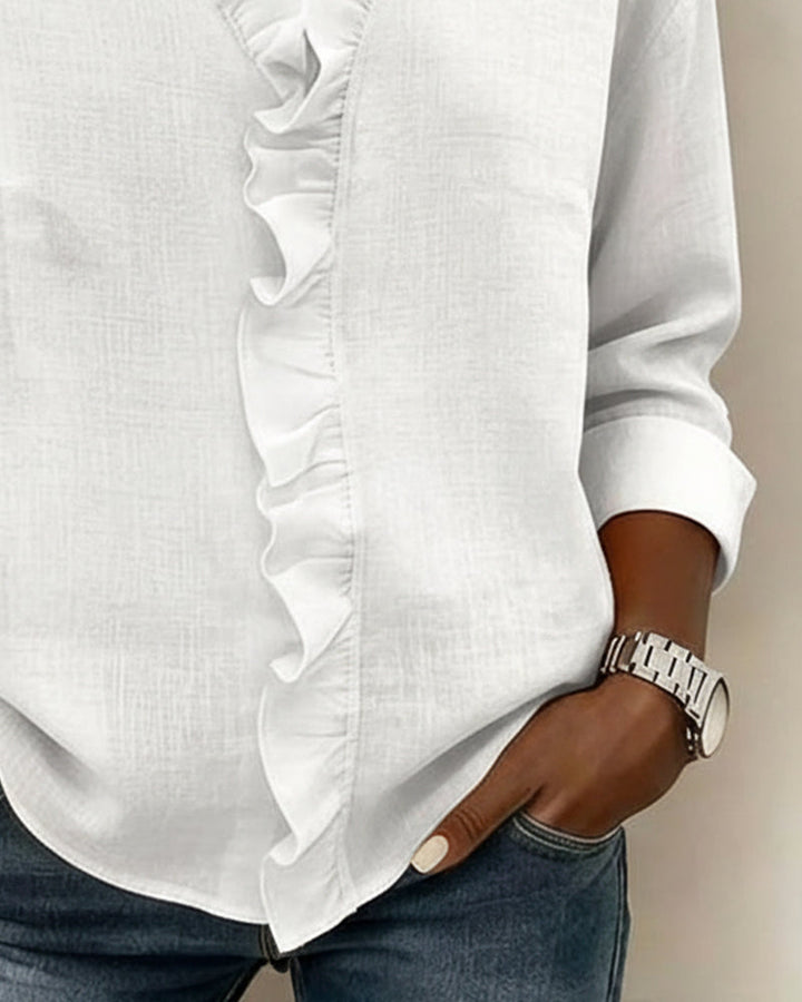 Model in a blue ruffle V-neck long-sleeve blouse, styled casually with jeans, full body shot.