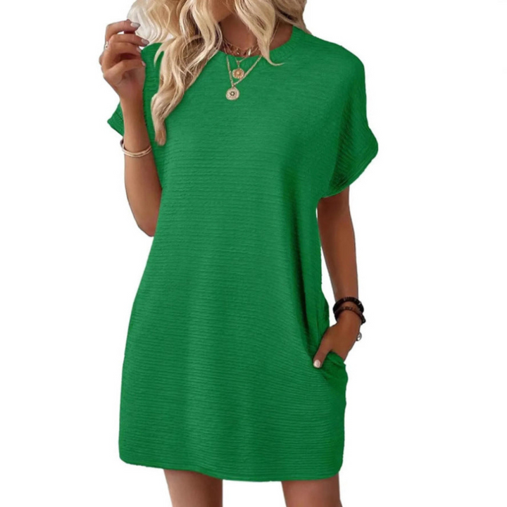 Outdoor scene with a woman wearing a green Valerie casual round neck dress, enjoying a bright, sunny day.