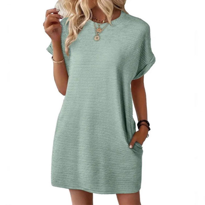 Full length shot of a woman wearing a light green Valerie casual round neck dress, walking in a park setting.