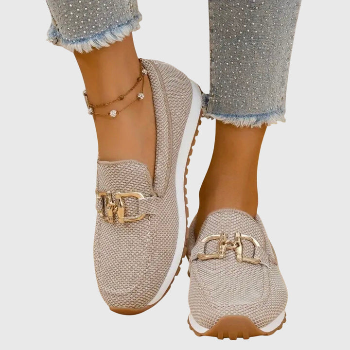 Close-up of a pair of beige orthopedic loafer sneakers on a light background, highlighting the texture and stitching.