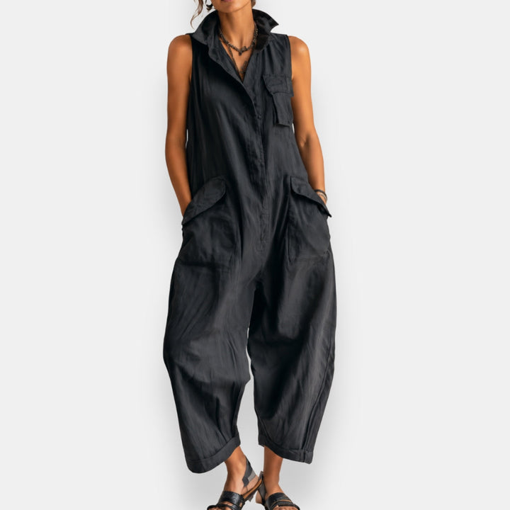 Full body shot of a woman walking in a black relaxed sleeveless jumpsuit, emphasizing the relaxed fit.