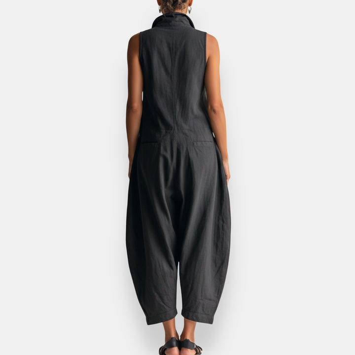 Back view of a woman wearing a khaki relaxed sleeveless jumpsuit, showing the overall silhouette.