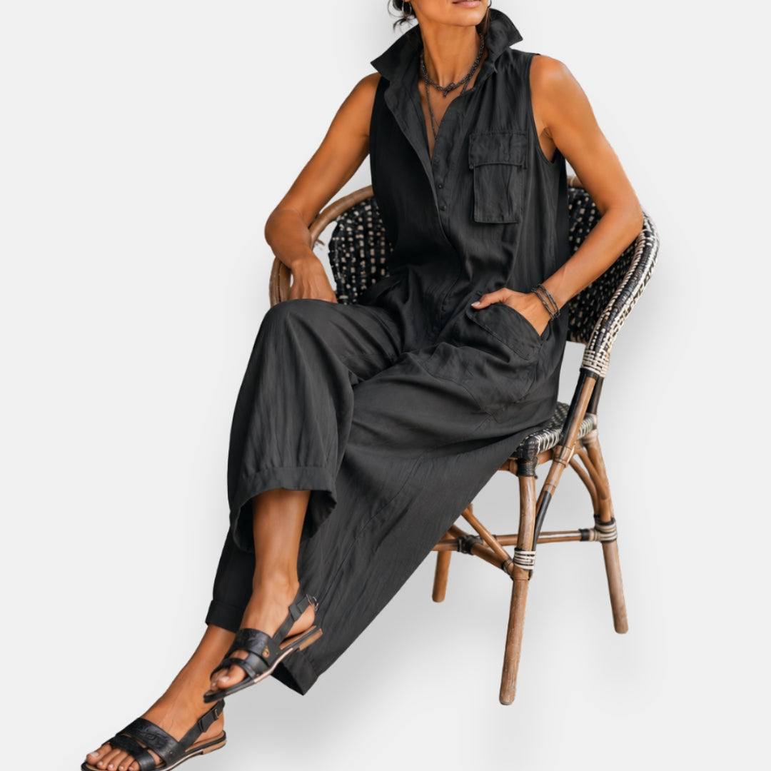 Woman sitting casually in a green relaxed sleeveless jumpsuit, demonstrating comfort and style.