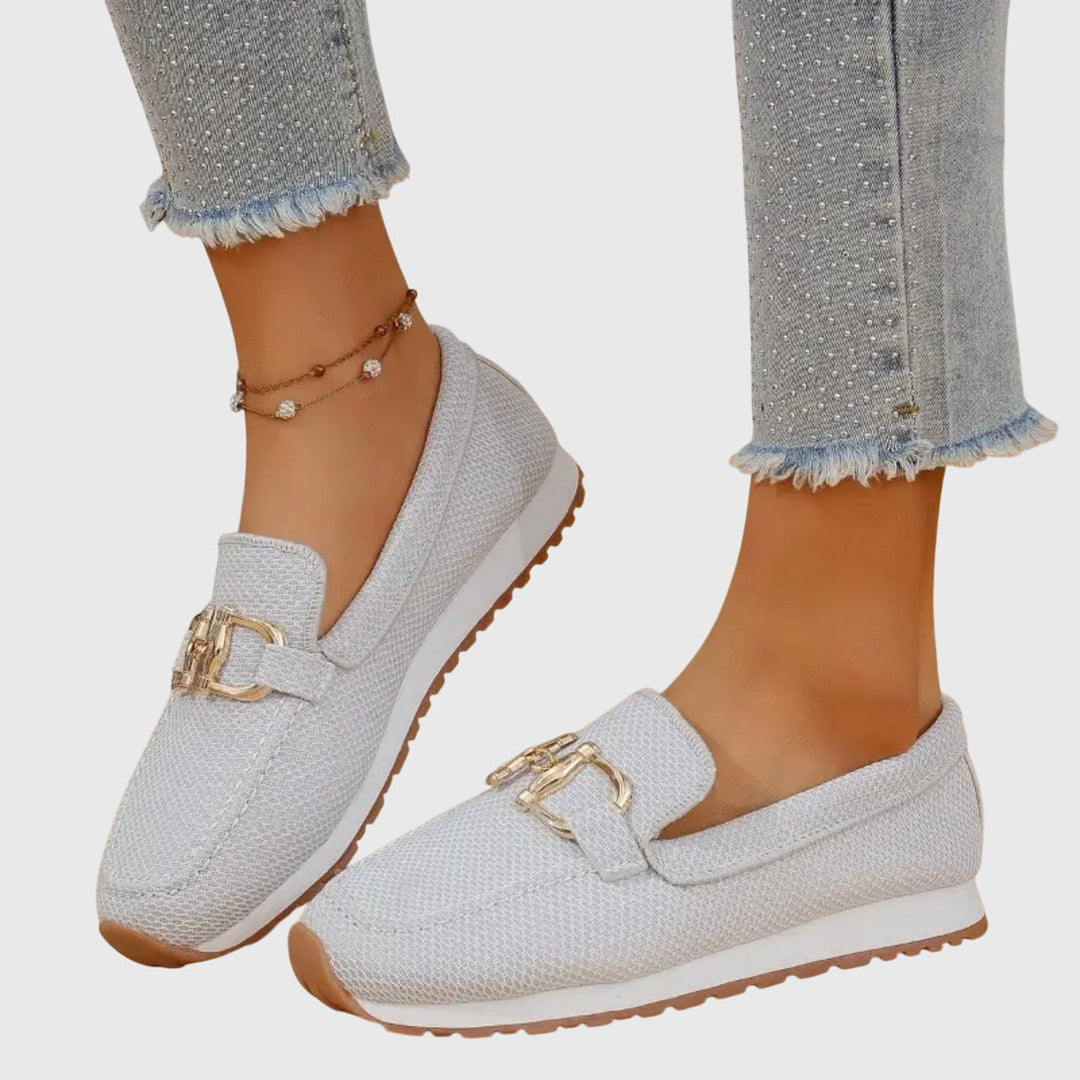 A stack of various colored orthopedic loafer sneakers (beige, white, blue, grey) creating a visually appealing arrangement.