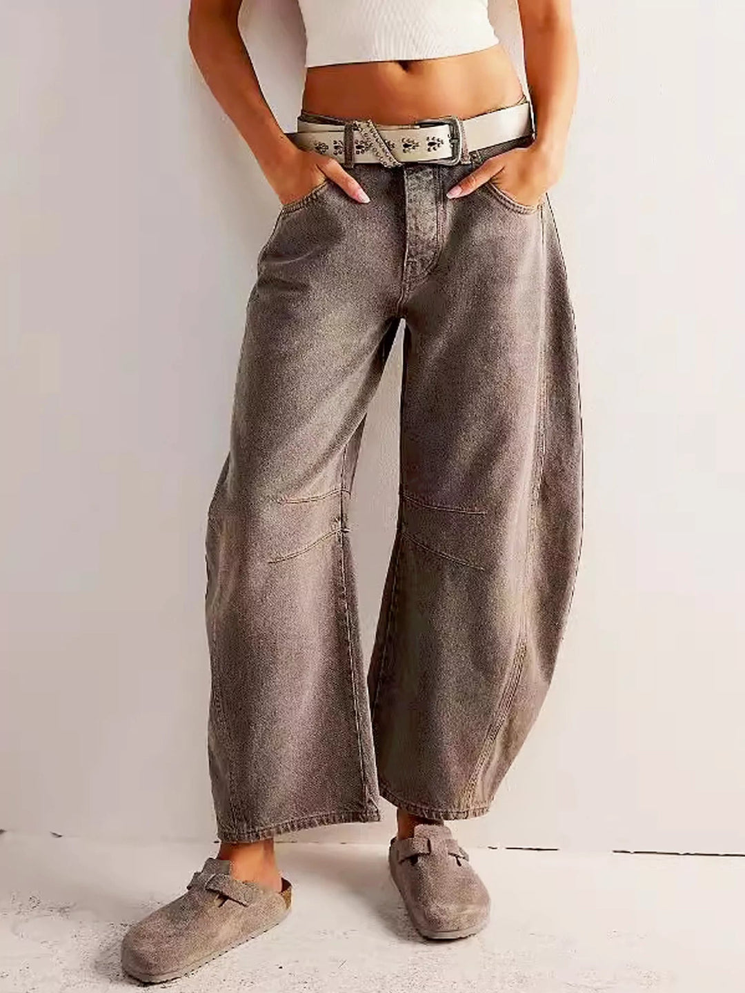 Detail shot of the button closure and belt loops on the waist of the barrel fit leopard print jeans.